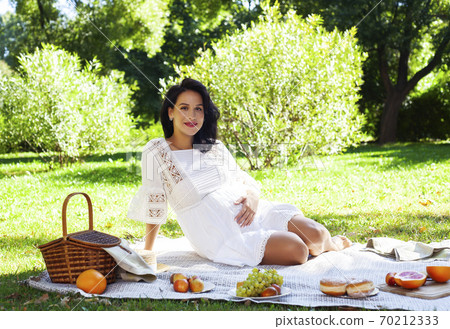 young pretty brunette pregnant woman outdoor in green park happy smiling, having picnic, lifestyle people concept 70212333