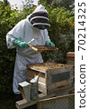 Beekeeper inspecting a frame of honey from hive 70214325