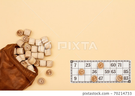 Wooden lotto barrels with brown bag and game card on beige background 70214733