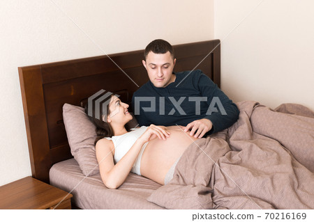 Pregnant woman with her husband in bed in the morning 70216169