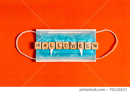 lettering Halloween on a medical protective mask on a black background with silhouettes of bats made lettering Halloween on a medical protective mask on a black background with silhouettes of bats made 70216823