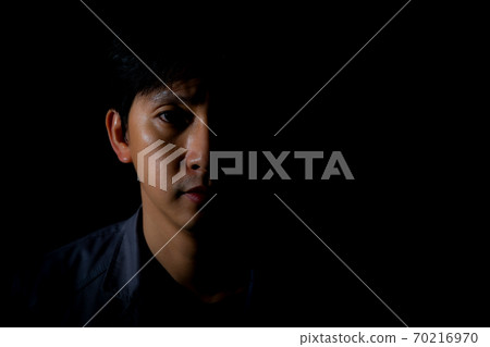 Close up portrait of a man on black background with half face in shadow and copyspace Close up portrait of a man on black background with half face in shadow and copyspace 70216970