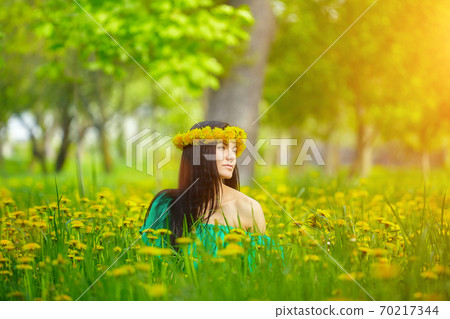 beautiful girl enjoys spring with a wreath of dandelions on her head 70217344