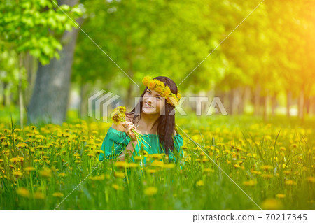 beautiful girl enjoys spring with a wreath of dandelions on her head 70217345