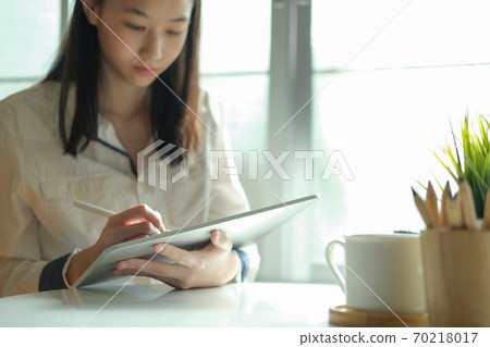 Young collage student using computer and digital tablet studying online. Young collage student using computer and digital tablet studying online. 70218017