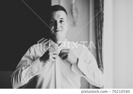 Grooms morning preparation. Handsome man getting dressed and preparing for the wedding 70218580