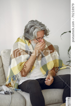 Old and sick senior man sitting at home 70218979