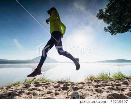 Slim man jogging on the beach early morning. 70219507
