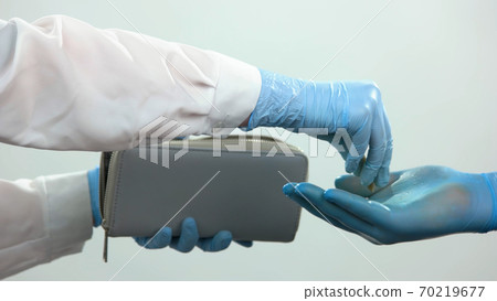 Close-up hands with protective gloves give coins. Close-up hands with protective gloves give coins. 70219677