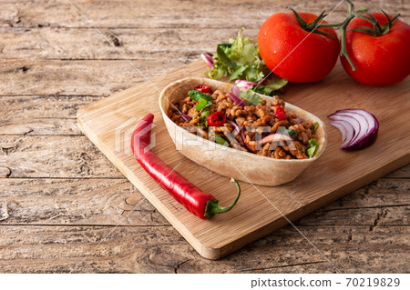 Mexican barquita taco with beef, chilli, tomato, onion and spices on wooden table Mexican barquita taco with beef, chilli, tomato, onion and spices on wooden table 70219829