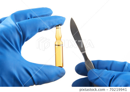 Medical scalpel and vial for injection in hands wearing blue gloves 70219941