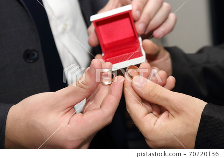 the groom and his witness carrying a wedding ring closeup 70220136