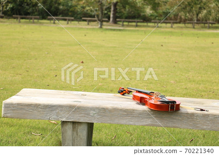 Violin placed on a wooden bench in the park 1 70221340