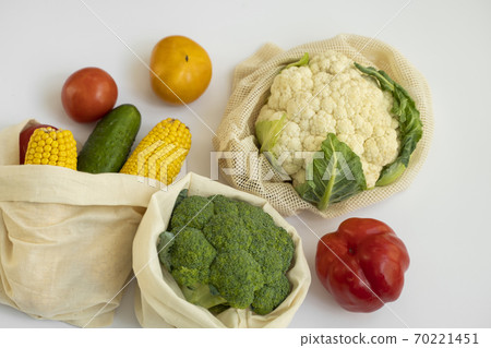 Vegetables in eco bag on white surface. Pepper, tomato, corn, cucumber, broccoli, cauliflower in reusable shopping eco friendly cotton fabric bags. Zero waste and plastic free concept. Sustainable. 70221451