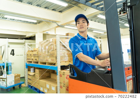 A man driving a forklift in a warehouse A man driving a forklift in a warehouse 70222482