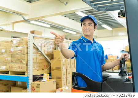 A man driving a forklift in a warehouse 70222489