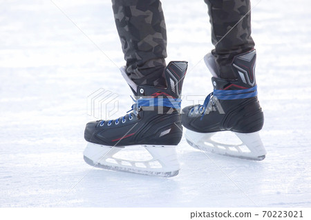 Legs of a man skating on an ice rink. Hobbies and sports. Vacations and winter activities Legs of a man skating on an ice rink. Hobbies and sports. Vacations and winter activities 70223021