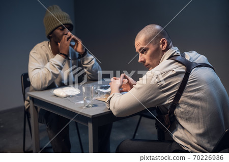 a black suspect in a hat under interrogation at the police station is worried invents an alibi a black suspect in a hat under interrogation at the police station is worried invents an alibi 70226986