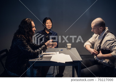 Two police officers are questioning a man with a tattooed face and long hair who is suspected of committing a crime. Consider the evidence in the case. Two police officers are questioning a man with a tattooed face and long hair who is suspected of committing a crime. Consider the evidence in the case. 70227000