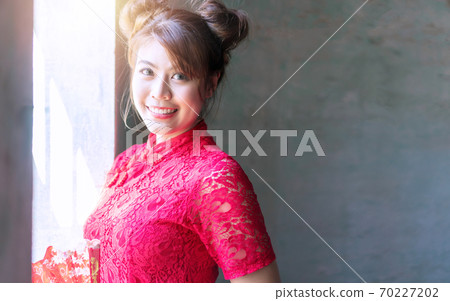 Attractive women wear cheongsam red dress looking at camera Attractive women wear cheongsam red dress looking at camera 70227202