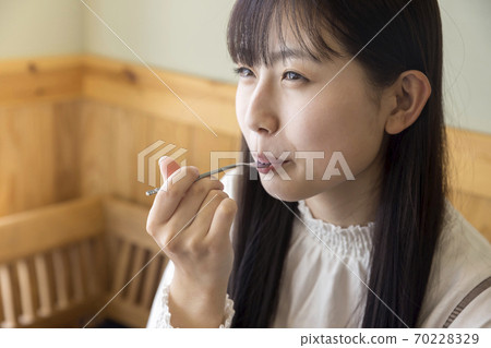 一個年輕的女大學生,吃一個看起來美味的蛋糕 一個年輕的女大學生,吃一個看起來美味的蛋糕 70228329