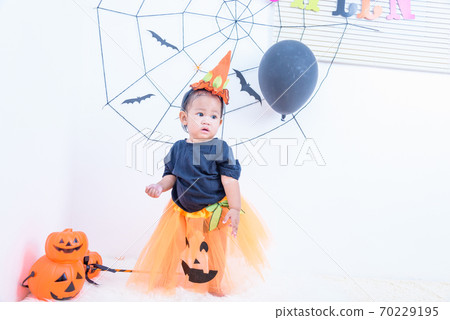 Funny happy baby girl in Halloween costume with pumpkin Jack 70229195