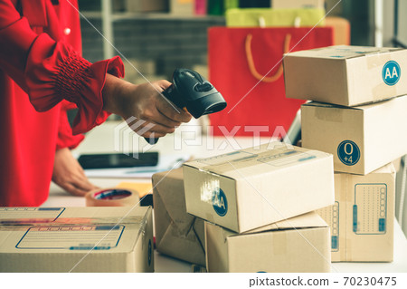Online seller works at home office and packs shipping delivery box to customer. Online seller works at home office and packs shipping delivery box to customer. 70230475