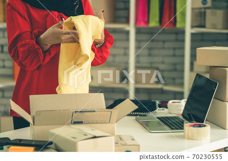 Online seller works at home office and packs shipping delivery box to customer. Online seller works at home office and packs shipping delivery box to customer. 70230555