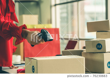 Online seller works at home office and packs shipping delivery box to customer. Online seller works at home office and packs shipping delivery box to customer. 70230663
