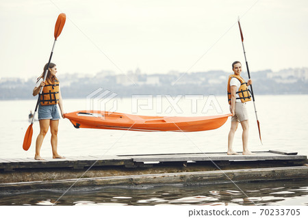 Women prepare to paddling on a lake in a kayak Women prepare to paddling on a lake in a kayak 70233705