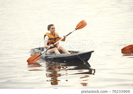 Woman paddling on a lake in a kayak Woman paddling on a lake in a kayak 70233909