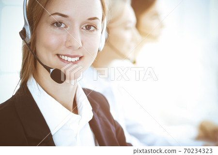 Call center and business people concept. Beautiful business woman with headphones consulting clients 70234323