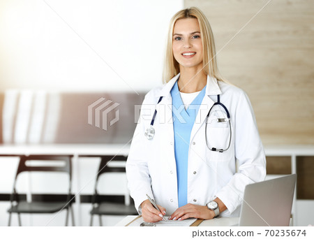 Doctor woman controls medication history records and exam results while using clipboard in sunny hospital . Medicine and healthcare concept 70235674