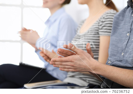 Business people clapping at meeting or conference, close-up of hands. Group of unknown businessmen and women in modern white office. Success teamwork, corporate coaching and applause concept Business people clapping at meeting or conference, close-up of hands. Group of unknown businessmen and women in modern white office. Success teamwork, corporate coaching and applause concept 70236752