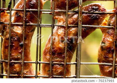 Grilling sausages on barbecue grill background Grilling sausages on barbecue grill background 70237993