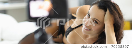 Woman in lingerie lies on bed and smiles. Woman in lingerie lies on bed and smiles. 70238897