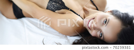 Smiling woman in underwear lies on bed. 70239381