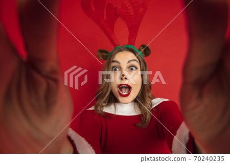 Beautiful woman like Christmas deer isolated on red background. Concept of 2021 New Year's, winter mood, holidays. 70240235