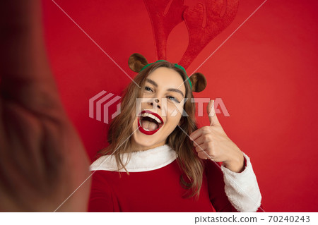 Beautiful woman like Christmas deer isolated on red background. Concept of 2021 New Year's, winter mood, holidays. 70240243