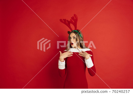 Beautiful woman like Christmas deer isolated on red background. Concept of 2021 New Year's, winter mood, holidays. Beautiful woman like Christmas deer isolated on red background. Concept of 2021 New Year's, winter mood, holidays. 70240257