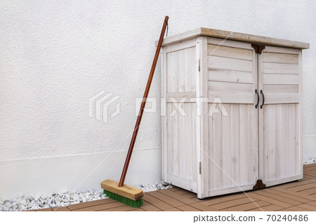 White storage seen from an angle and a deck brush leaning against White storage seen from an angle and a deck brush leaning against 70240486