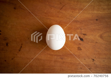 A white fresh egg on a wooden table 70240756