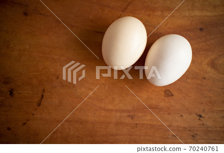 Two eggs on a wooden board 70240761