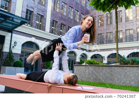 Two girls drink coffee in acroyoga position Two girls drink coffee in acroyoga position 70241307