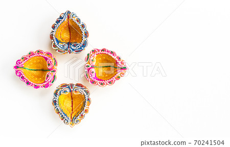 Happy Diwali - Clay Diya lamps lit during Dipavali, Hindu festival of lights celebration. Colorful traditional oil lamp diya on white background Happy Diwali - Clay Diya lamps lit during Dipavali, Hindu festival of lights celebration. Colorful traditional oil lamp diya on white background 70241504