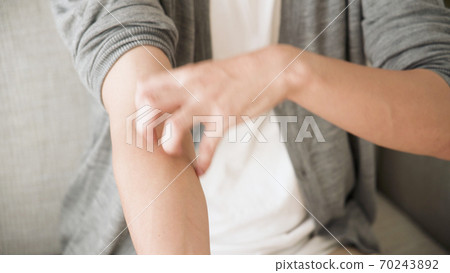 Young man scratching his arm 70243892
