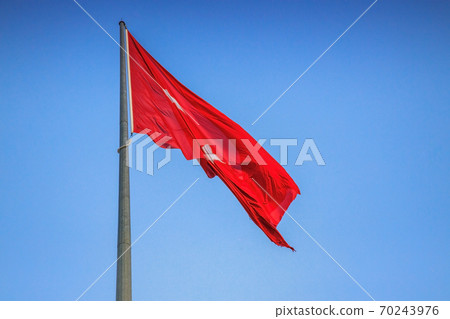 The Turkish flag flutters against a clear blue sky The Turkish flag flutters against a clear blue sky 70243976