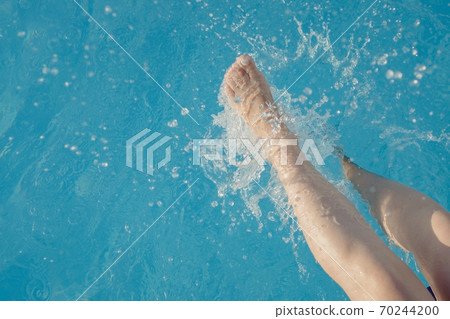cropped young european woman kicks in the pool splashes water. Concept, carefree, summer, vacation 70244200