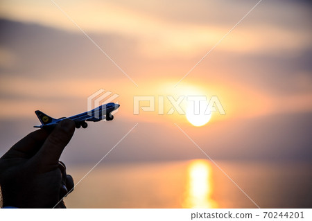 toy plane in hand against the backdrop of a beautiful sea sunset. Silhouette. Copy space toy plane in hand against the backdrop of a beautiful sea sunset. Silhouette. Copy space 70244201