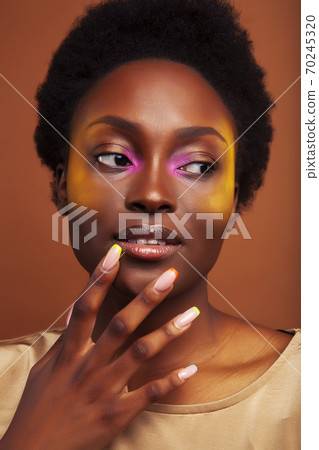 pretty young african american woman with curly hair posing cheerful gesturing on brown background, lifestyle people concept 70245320